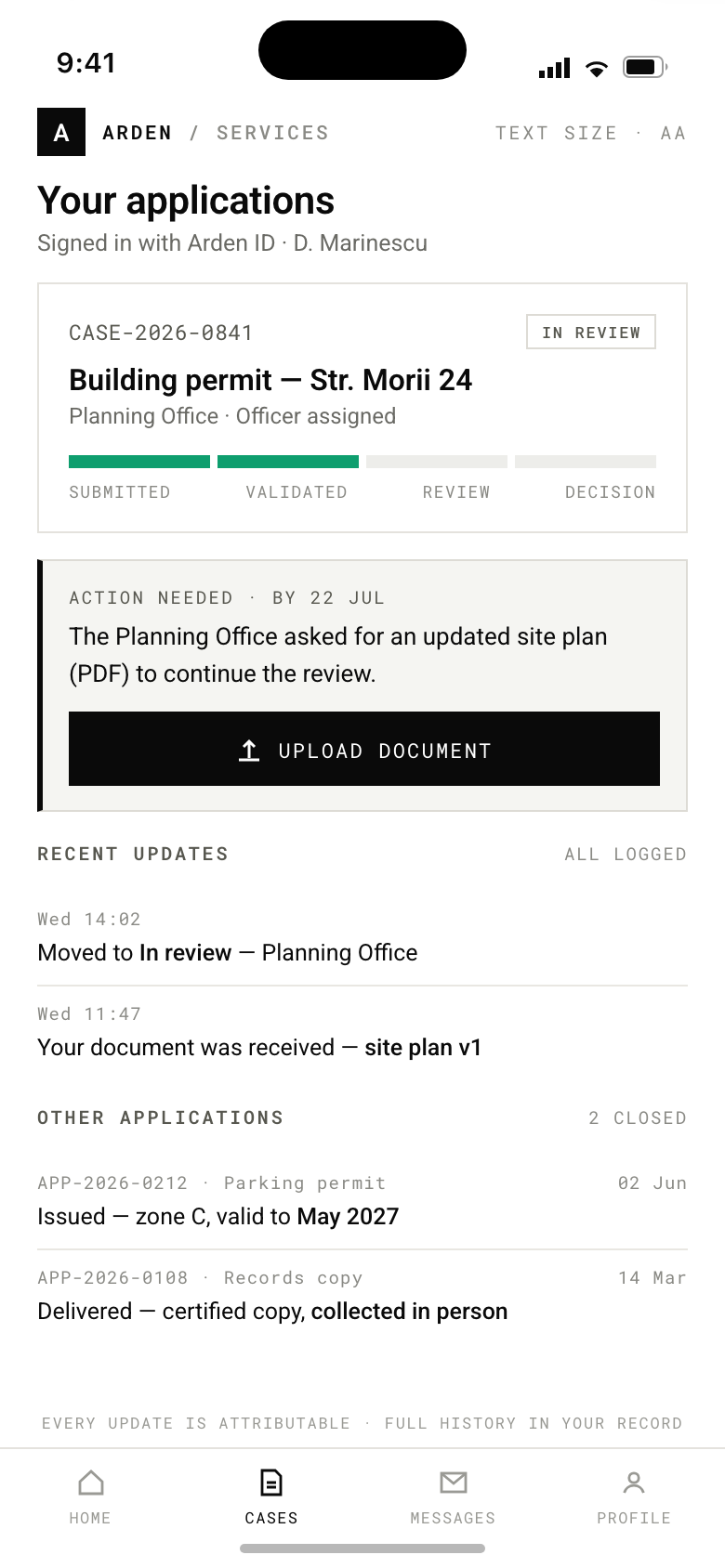Accessible citizen services phone app showing a building permit application in review at the Planning Office, with a four-step progress bar half filled in green. An action-needed panel requests an updated site plan by 22 July with an upload button. Below are logged updates with timestamps and two closed applications, and a footer stating every update is attributable with full history in the record.